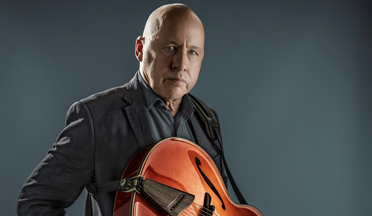 Mark Knopfler holding a guitar