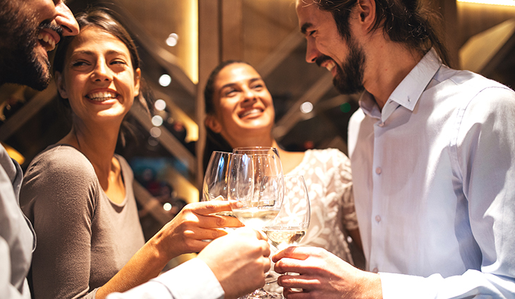 people smiling and clinking wine glasses
