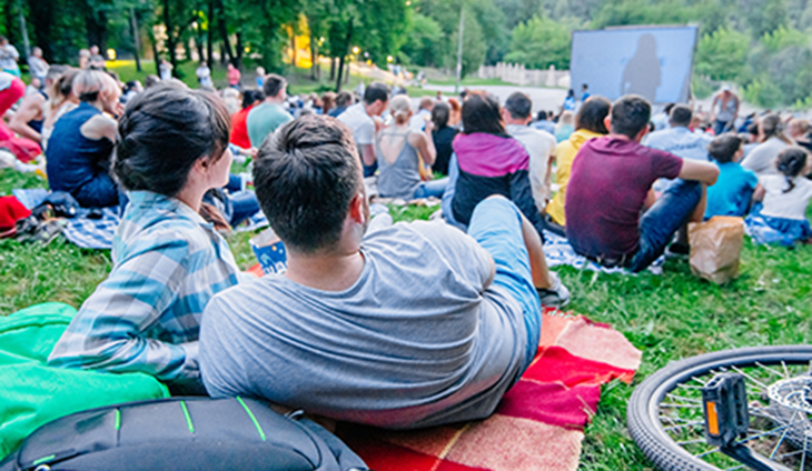 A couple sitting on a blanket watching an outdoor movie